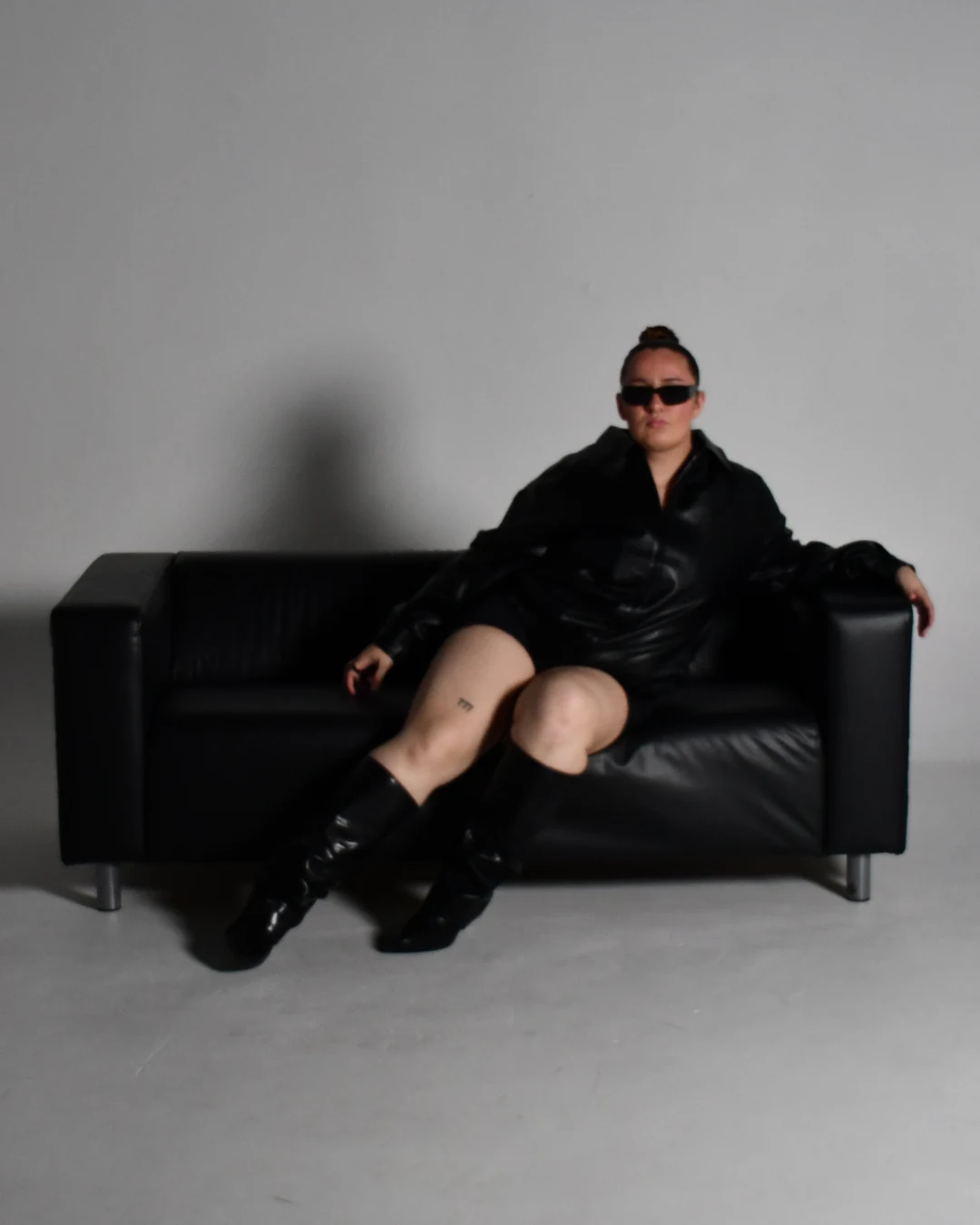 Sabrina sitting on a black leather sofa